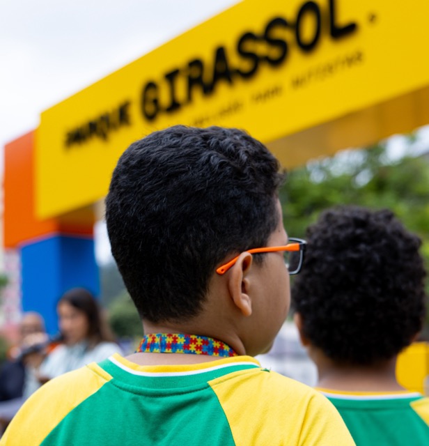 Crianças em frente ao arco do Parque Girassol, com colar de autismo